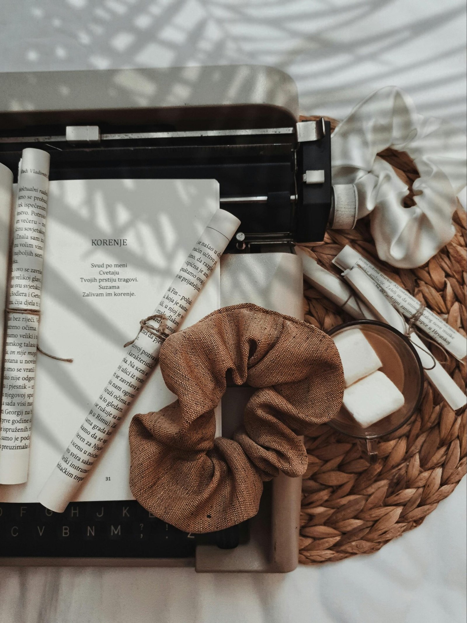 pexels-photo-4982669-4982669 A creative flat lay of a vintage typewriter surrounded by paper rolls and scrunchies, set against a woven background.